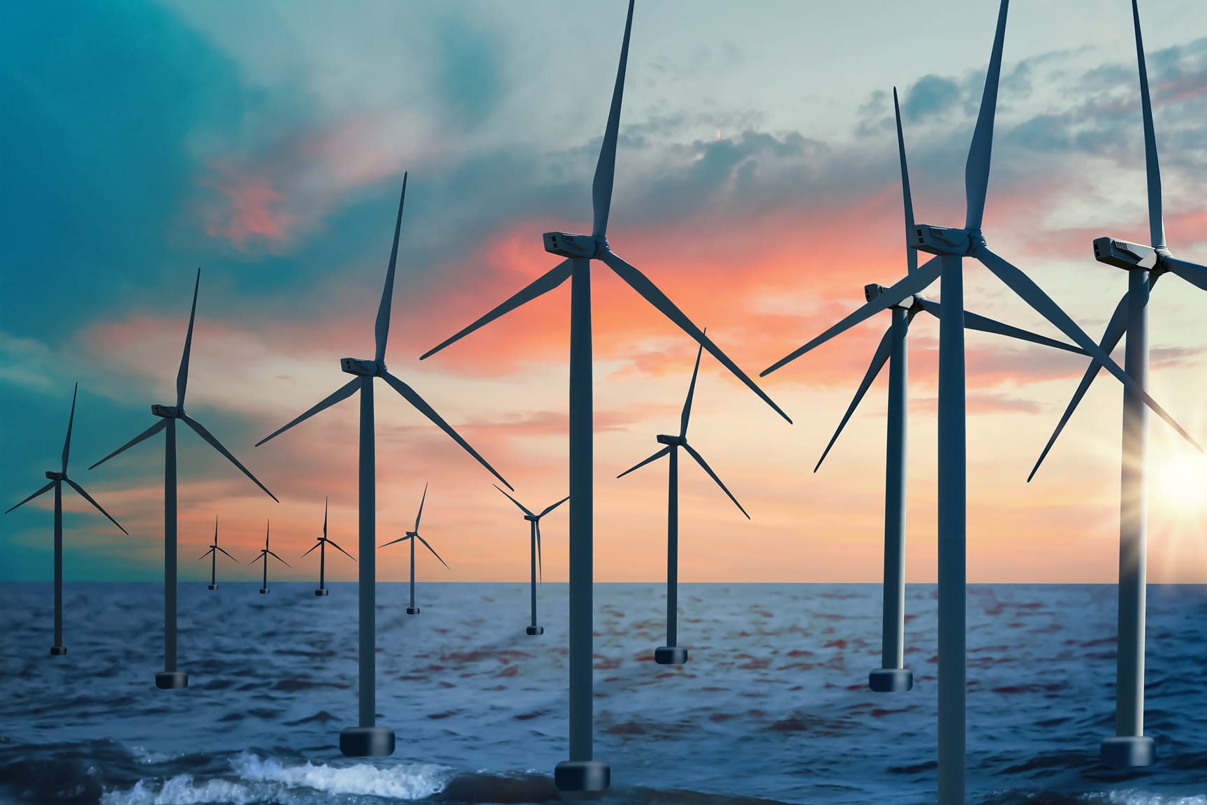 Offshore wind farm depicted by a group of turbines standing in the ocean set against a backdrop of sunset. 