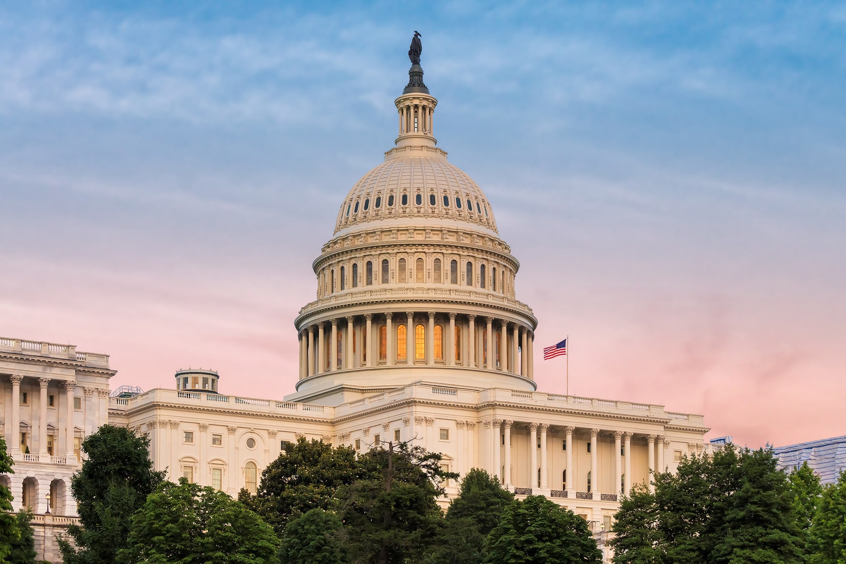 The image features the iconic dome of the United States Capitol building under a pastel-colored evening sky. 