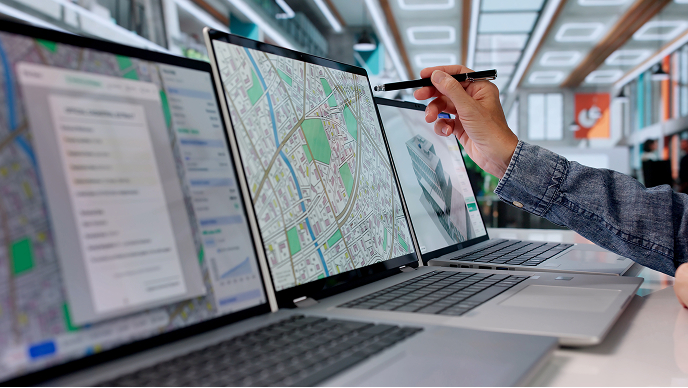 A person uses a stylus to edit a detailed city map displayed on a laptop screen