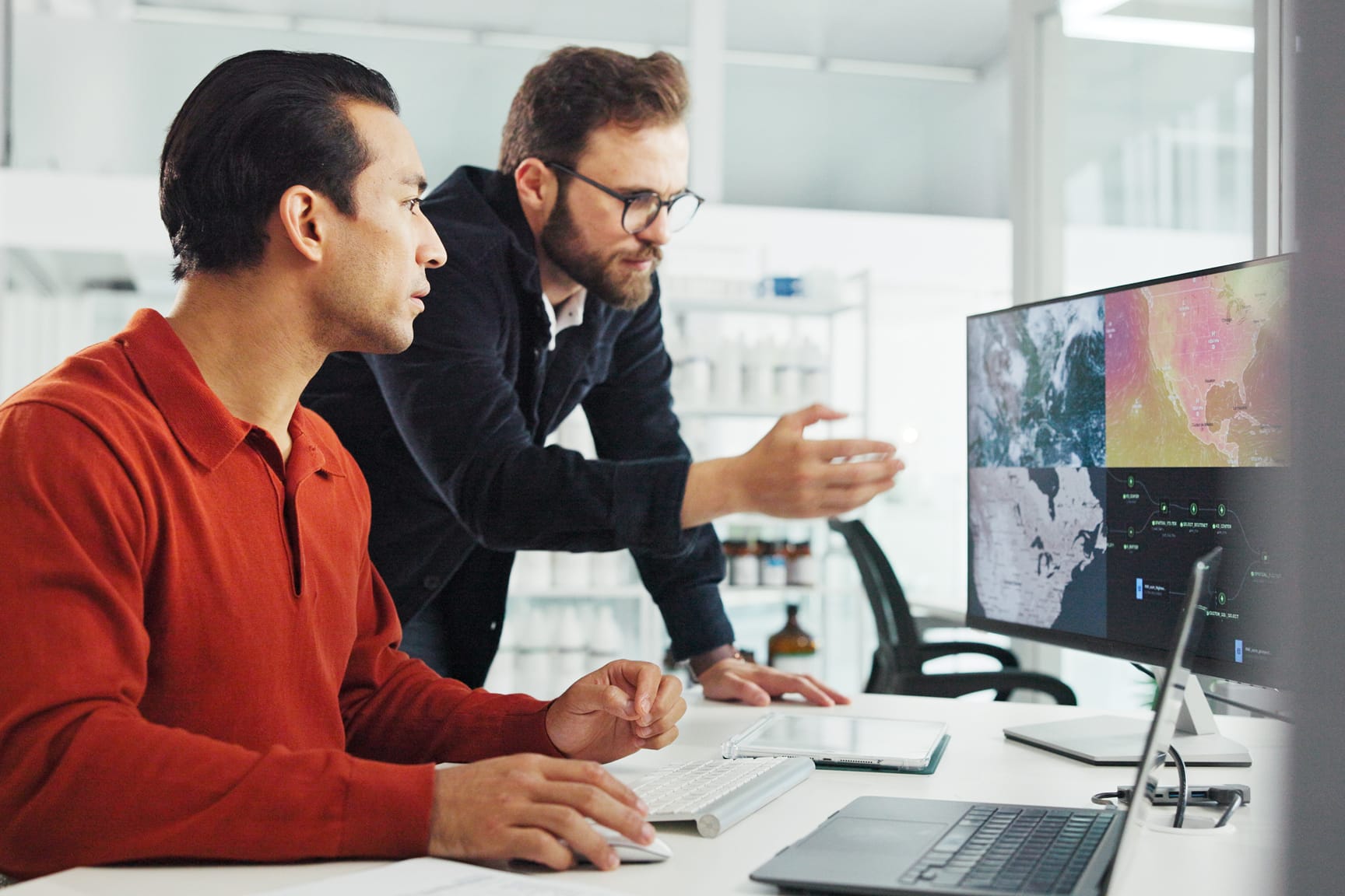 Two individuals are engaged in a collaborative discussion in a bright, modern office environment. 