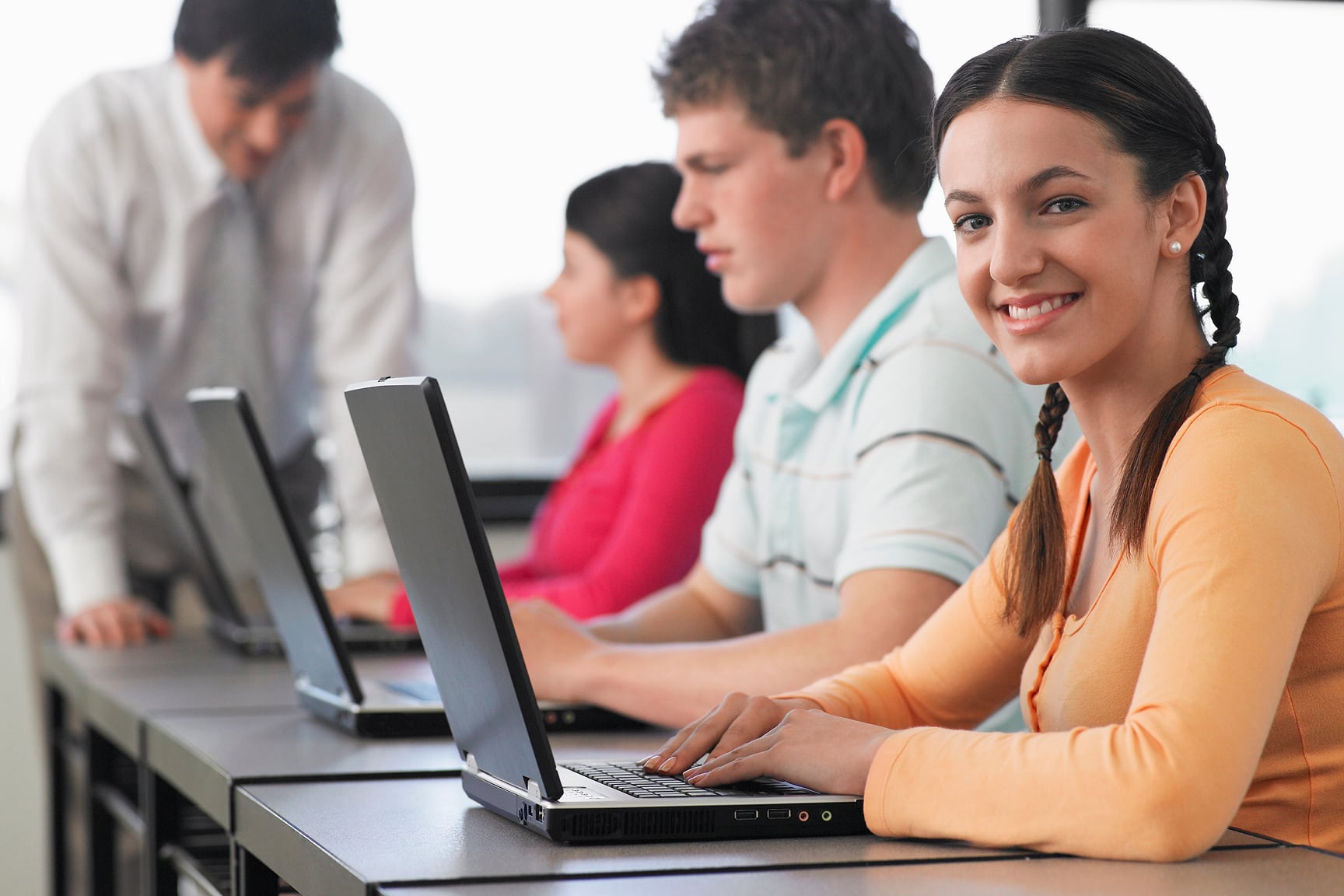 high school students smiling at their laptops.