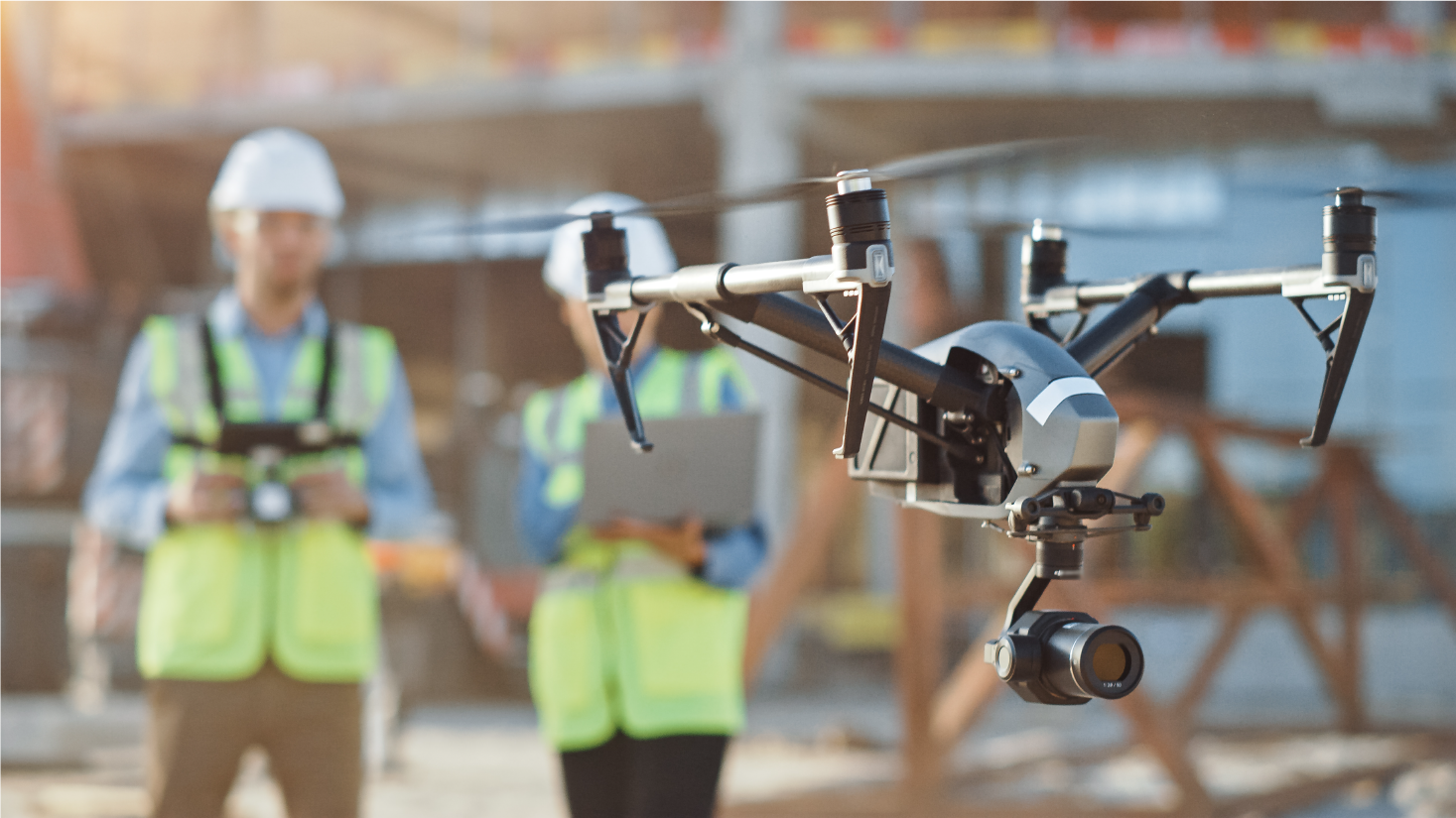 Two men in a hardhat and vest working with a drone, ready for aerial inspection or surveying tasks.