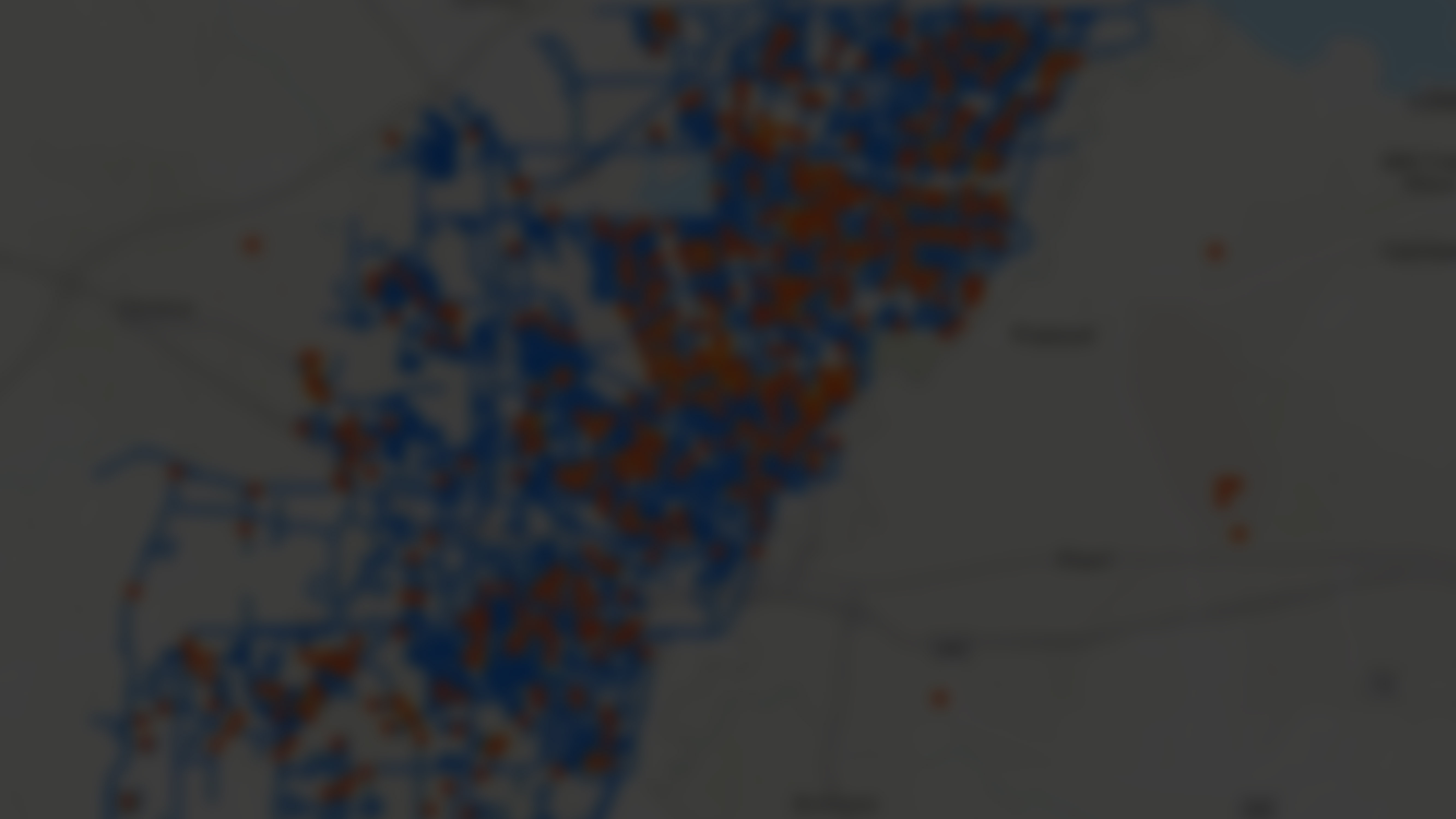 The image shows a blurred map featuring numerous blue and red dots scattered across a city layout.