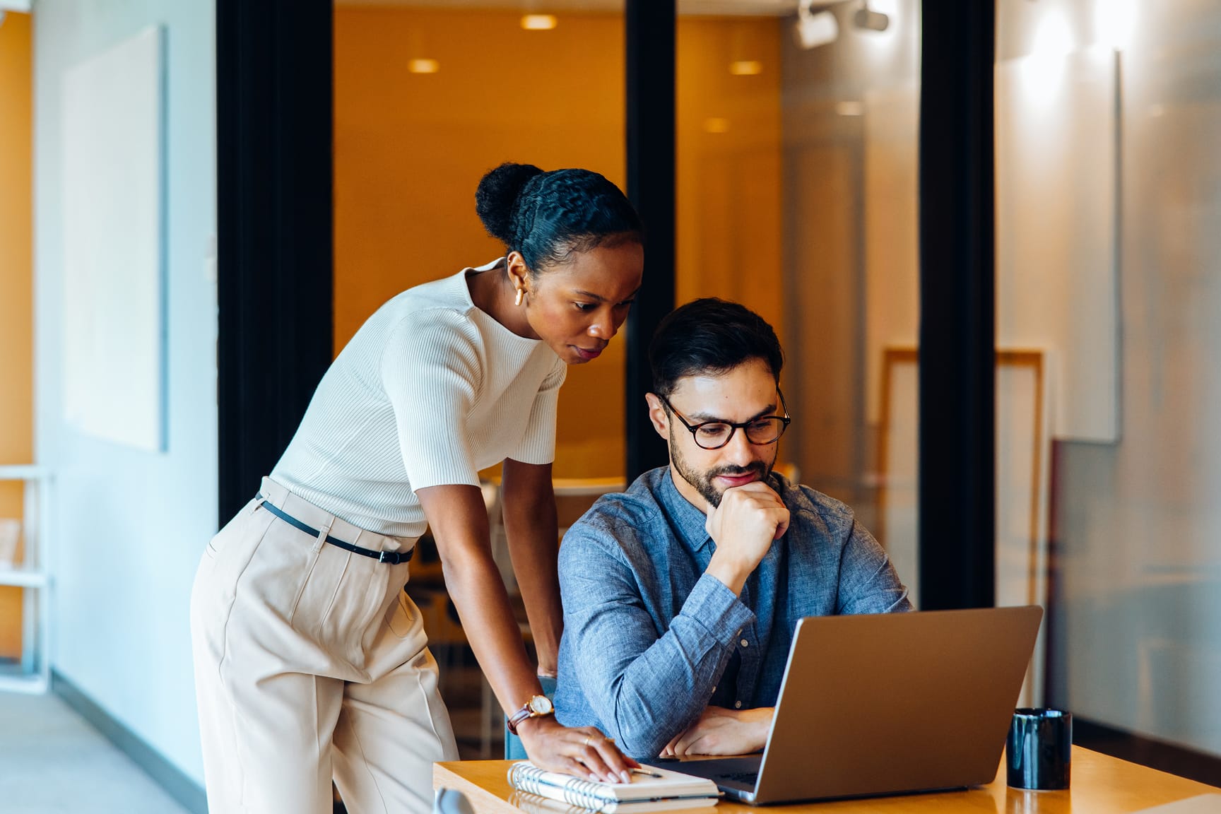 Two adults are engaged in a collaborative work session at a desk in a contemporary office setting. 