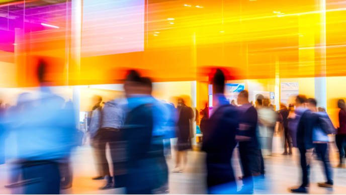 The image shows a group of people moving through a brightly lit, contemporary indoor space.