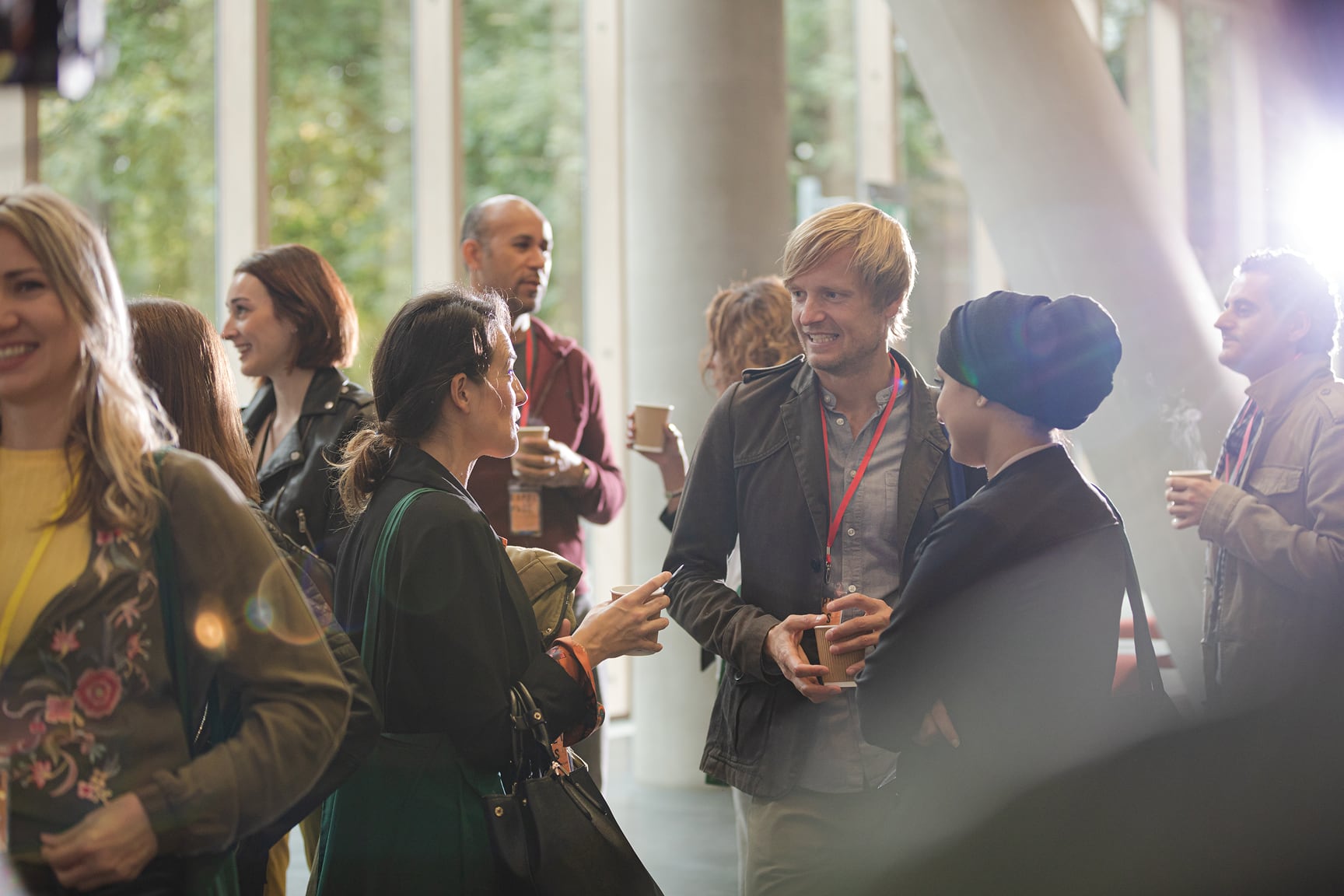 A diverse group of adults are gathered indoors, engaging in conversation and networking