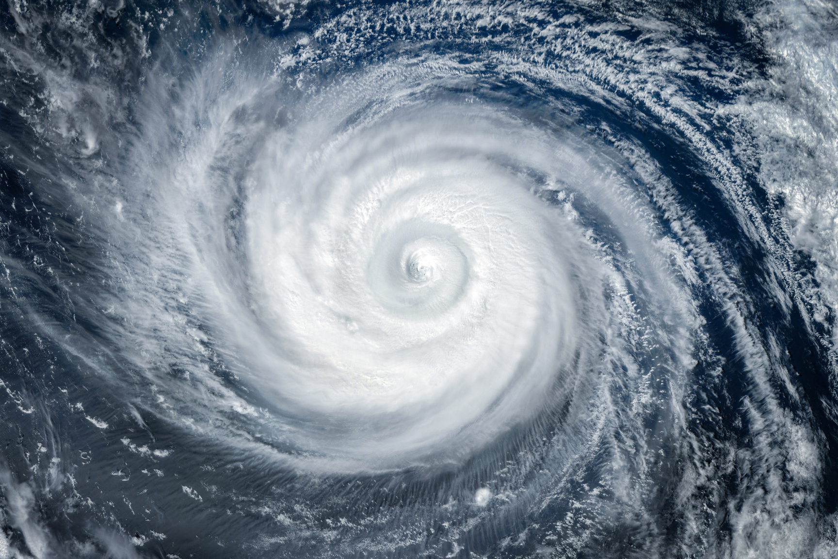 Blurred swirling clouds showing the center of a hurricane over the water.