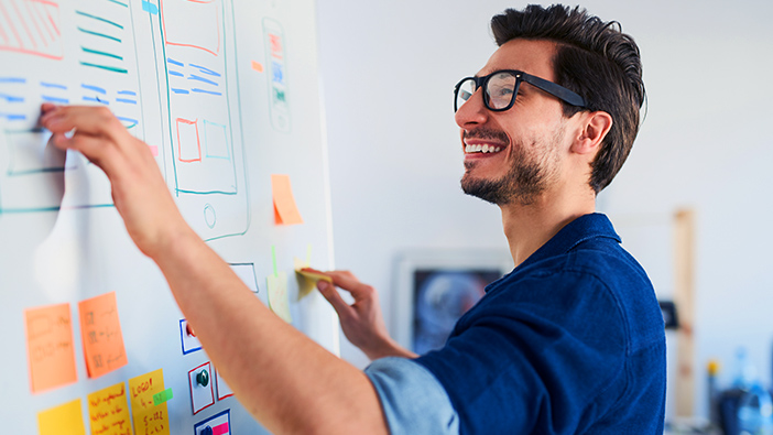 Professor smiling and pointing to content on a white board