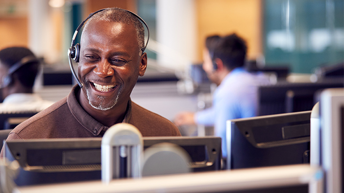 Customer service representative smiling while talking to a customer on his headset