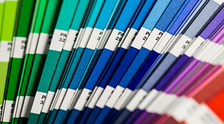A close-up image of a stack of rainbow paper swatches arranged by color