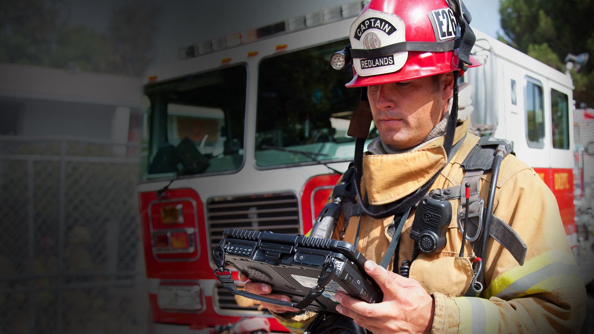 Firefighter looking at a tablet in front of an engine.