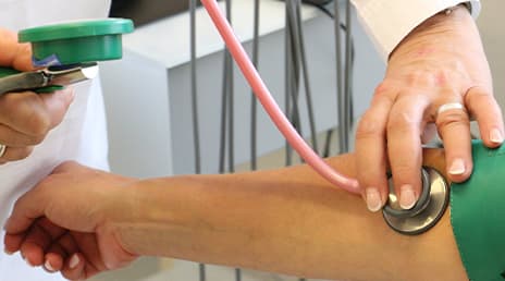 A close-up of a medical professional using a stethoscope to determine a patient’s blood pressure