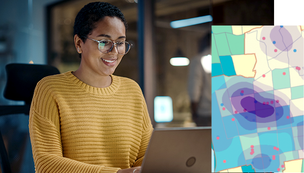 A person working in an office on a laptop with a colorful digital map in the foreground