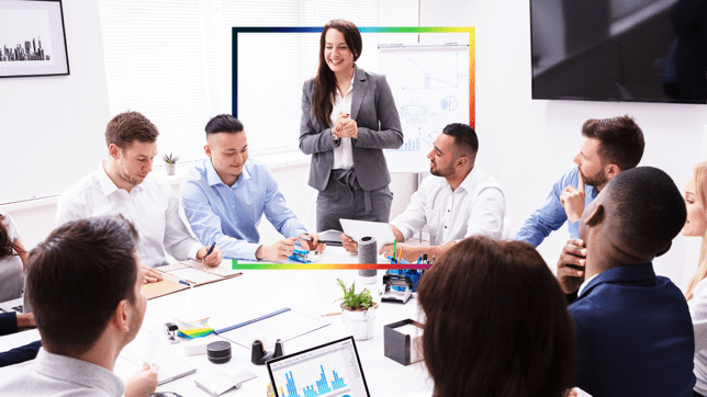 A group of professionals in a conference room taking notes, looking at graphs, and sharing ideas for new business opportunities