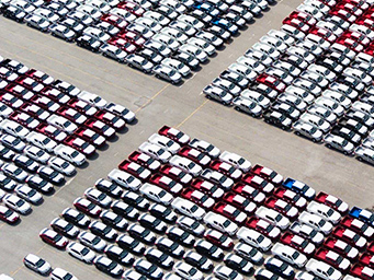 An aerial view of hundreds of rows of vehicles parked in an outdoor inventory lot