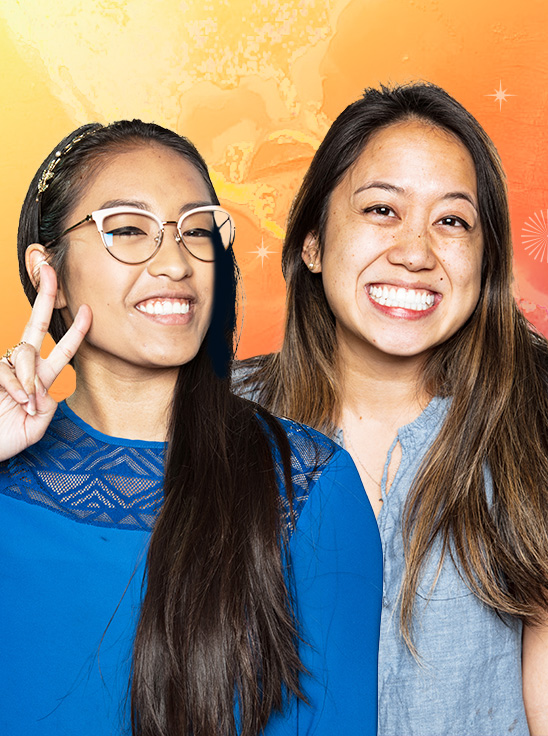 Two people smiling and one of them holding up the peace sign