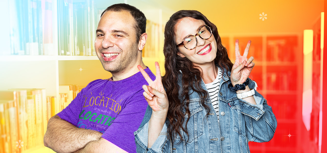 Two people smiling broadly and one of them holding both hands up in peace signs