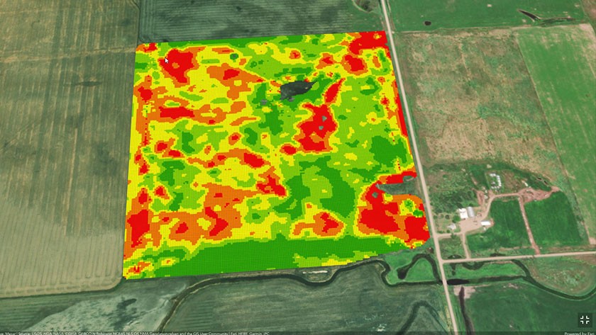 A satellite photo of sprawling green and yellow croplands with a heat map overlay with crop health data in shades of yellow and red