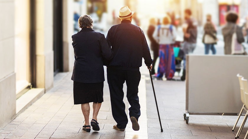 Older couple walking together on a city sidewalk