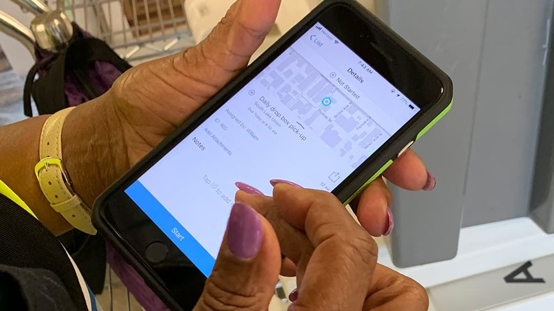 A person interacts with a smartphone displaying a navigation or location-based app interface.