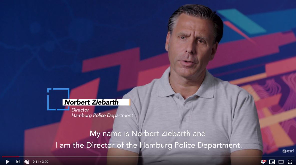 Man in a gray polo speaking on camera, identified as Norbert Ziebarth, Director of the Hamburg Police Department.