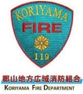 An embroidered badge featuring the Koriyama Fire Department logo prominently displayed. 