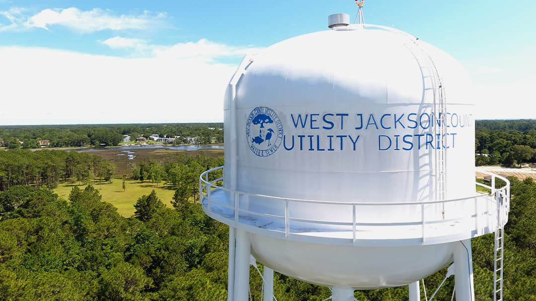 A large white water tower prominently displays the text 'West Jackson County Utility District' along with a circular logo.
