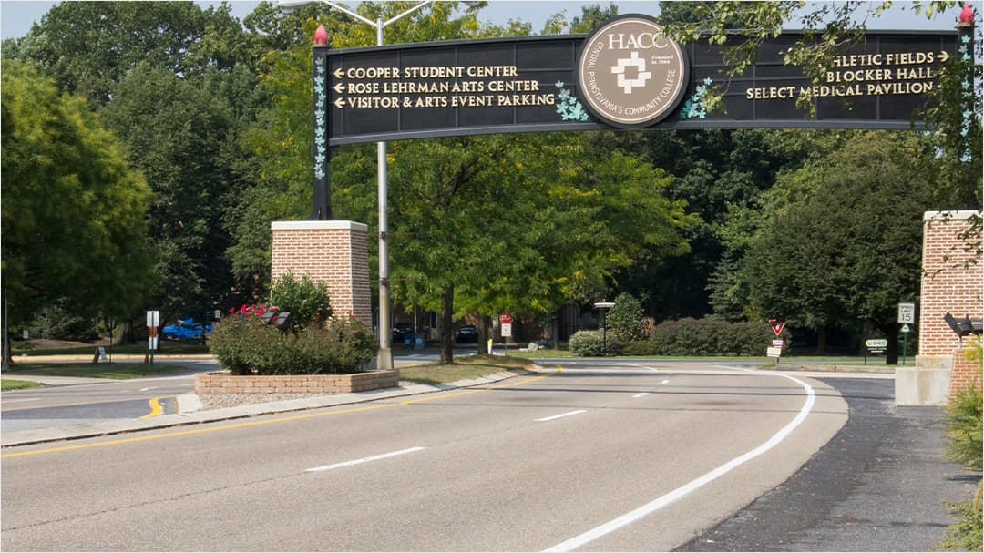 A road leading to the HACC campus is marked by a prominent entrance sign. 