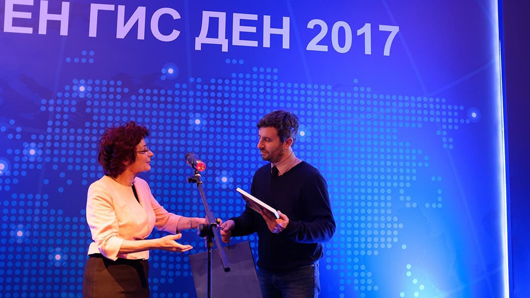 Asparuh Kamburov on stage with a presenter, accepting an award