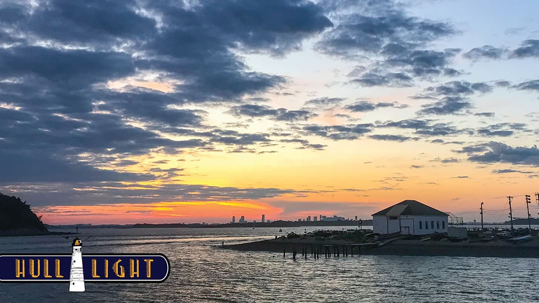 A serene coastal scene featuring a vibrant sunset over calm waters.