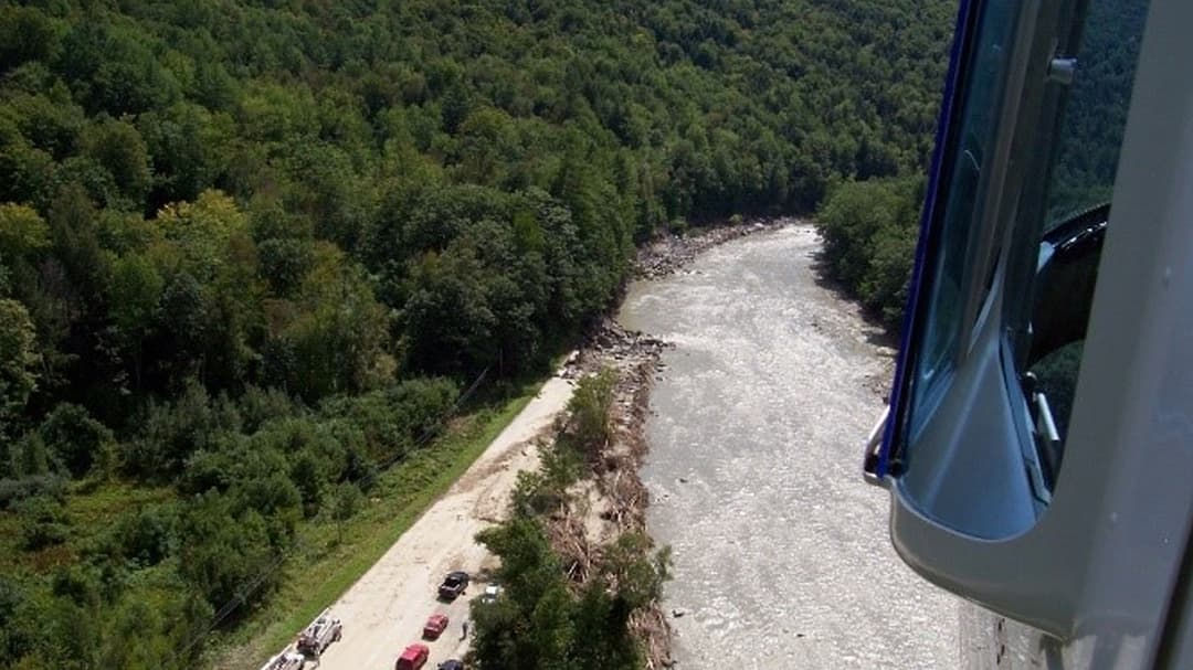 An aerial perspective captures a winding river surrounded by dense green forest. 