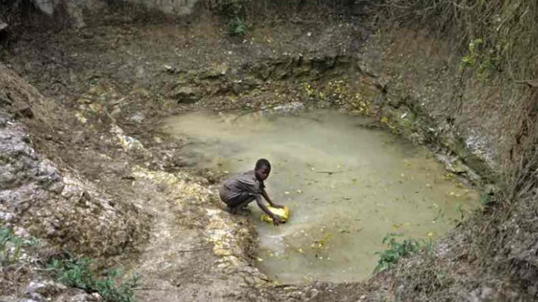 Ugandan girl fetches water from a stagnant natural water source