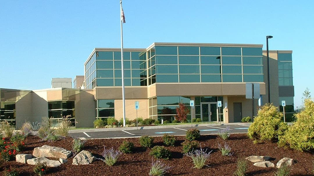 A contemporary office building featuring large glass windows and a beige facade. 