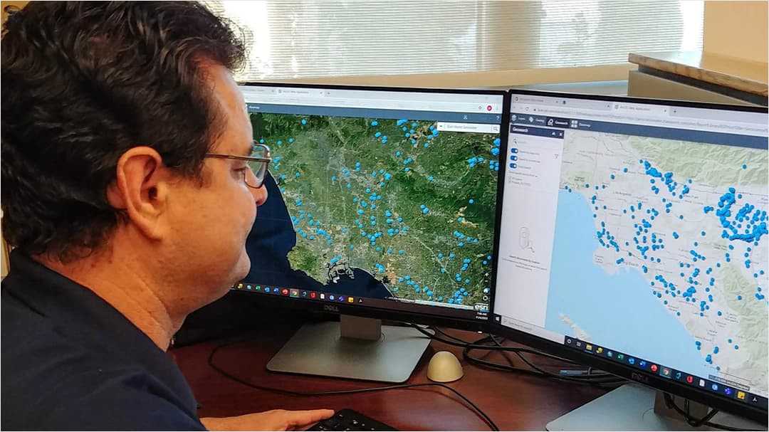 Employee looking at maps on computer screens