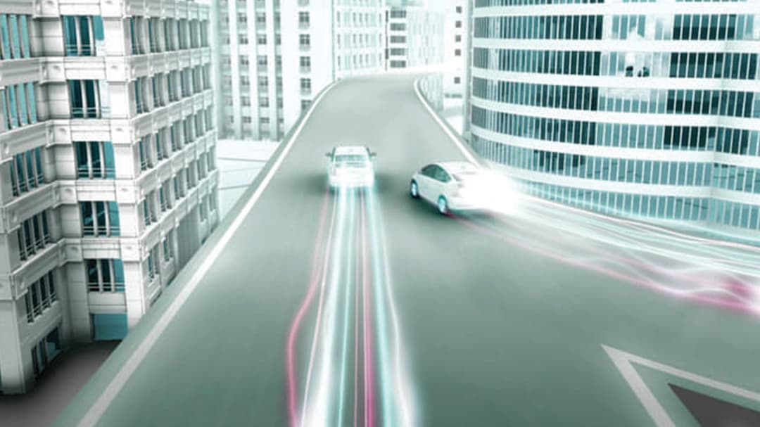 Blick in eine Straße mit zwei Prius-Fahrzeugen, die Lichtschweife hinter sich herziehen