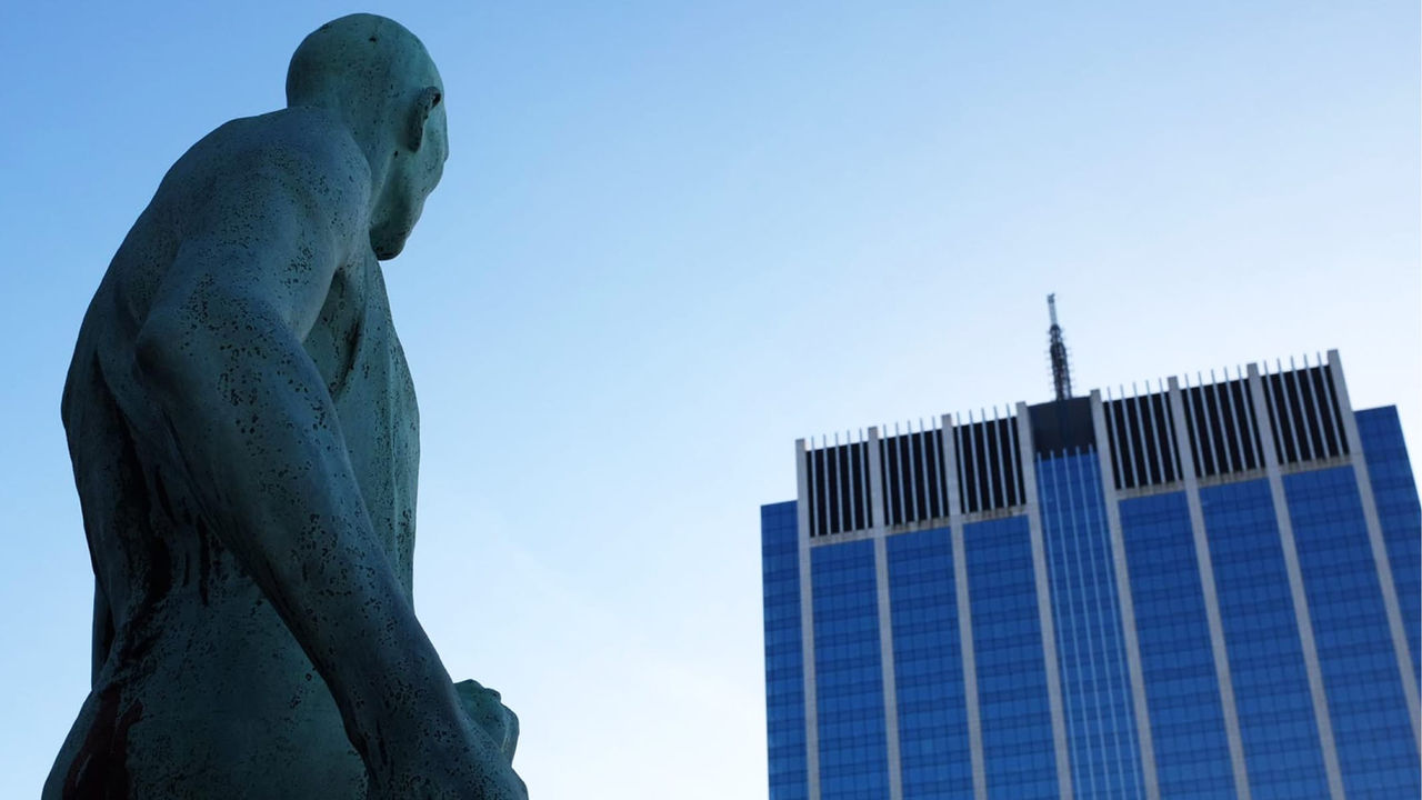 A tall corporate building with a statue in the foreground