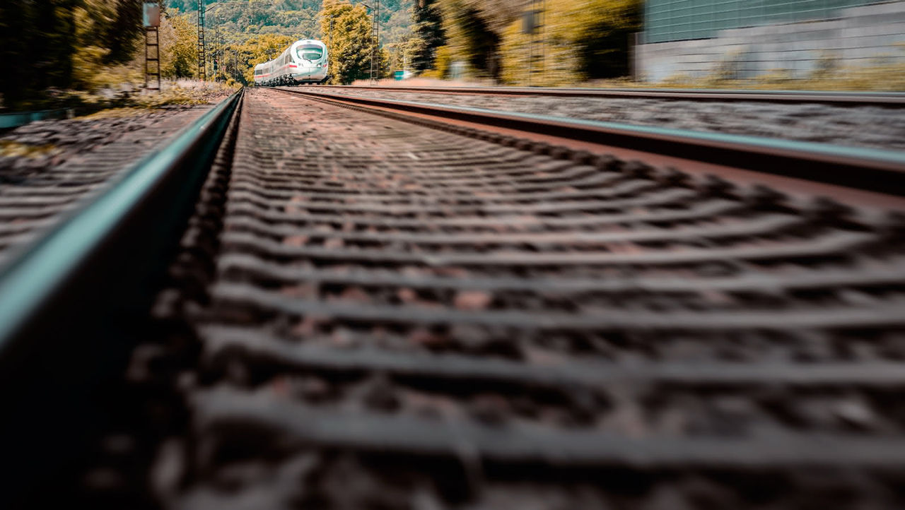 Low-angle view of a train approaching on railway tracks with trees in the background
