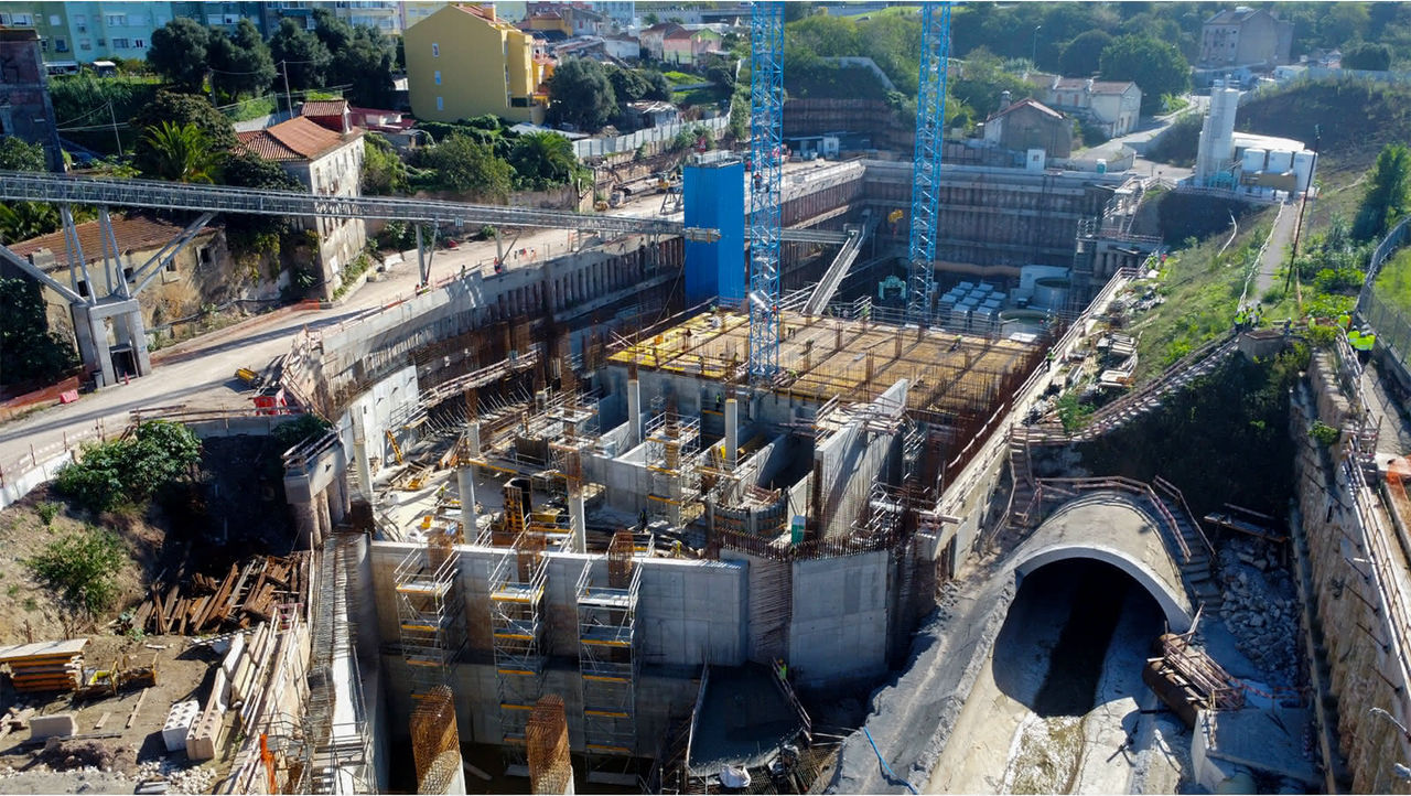 Aerial view of a large construction site with cranes, concrete structures, and excavation work in Lisbon