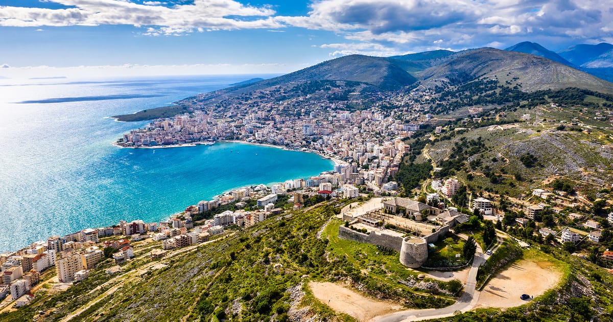 A sweeping aerial view of a coastal city nestled along a turquoise bay