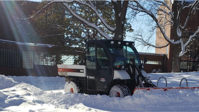 A utility truck removes snow from campus pathways