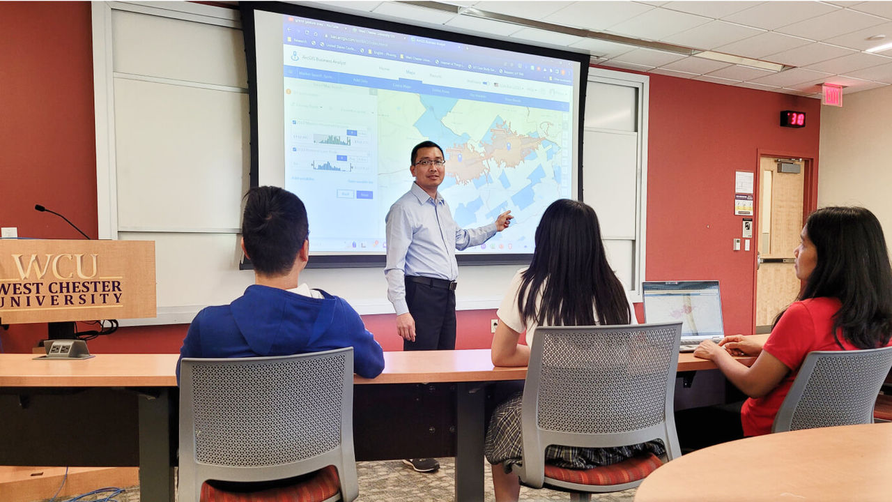 Professor pointing at a map in classroom teaching students.