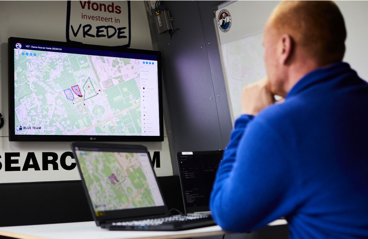 Veteran Search Team commander stares at desktop map with a polygon search area highlighted in purple in the command-and-control app