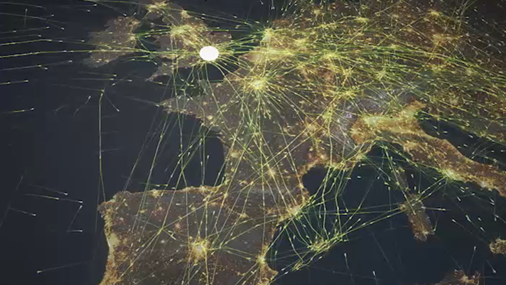 A nighttime aerial view of Europe with glowing lines connecting the cities to form a network across the continent 