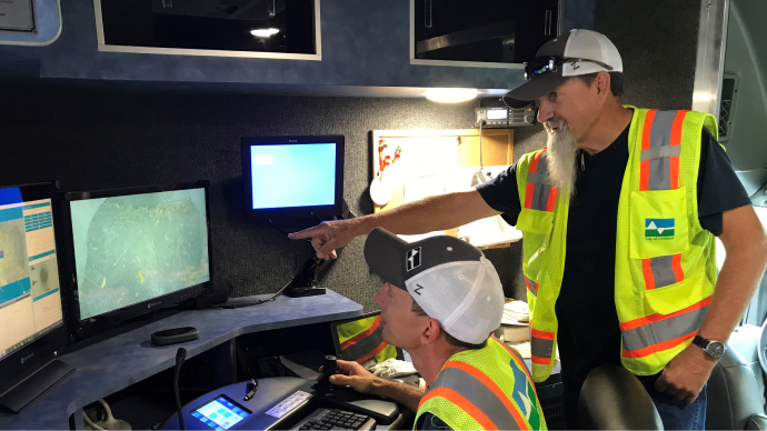 workers viewing desktop monitors showing sewer inspection data
