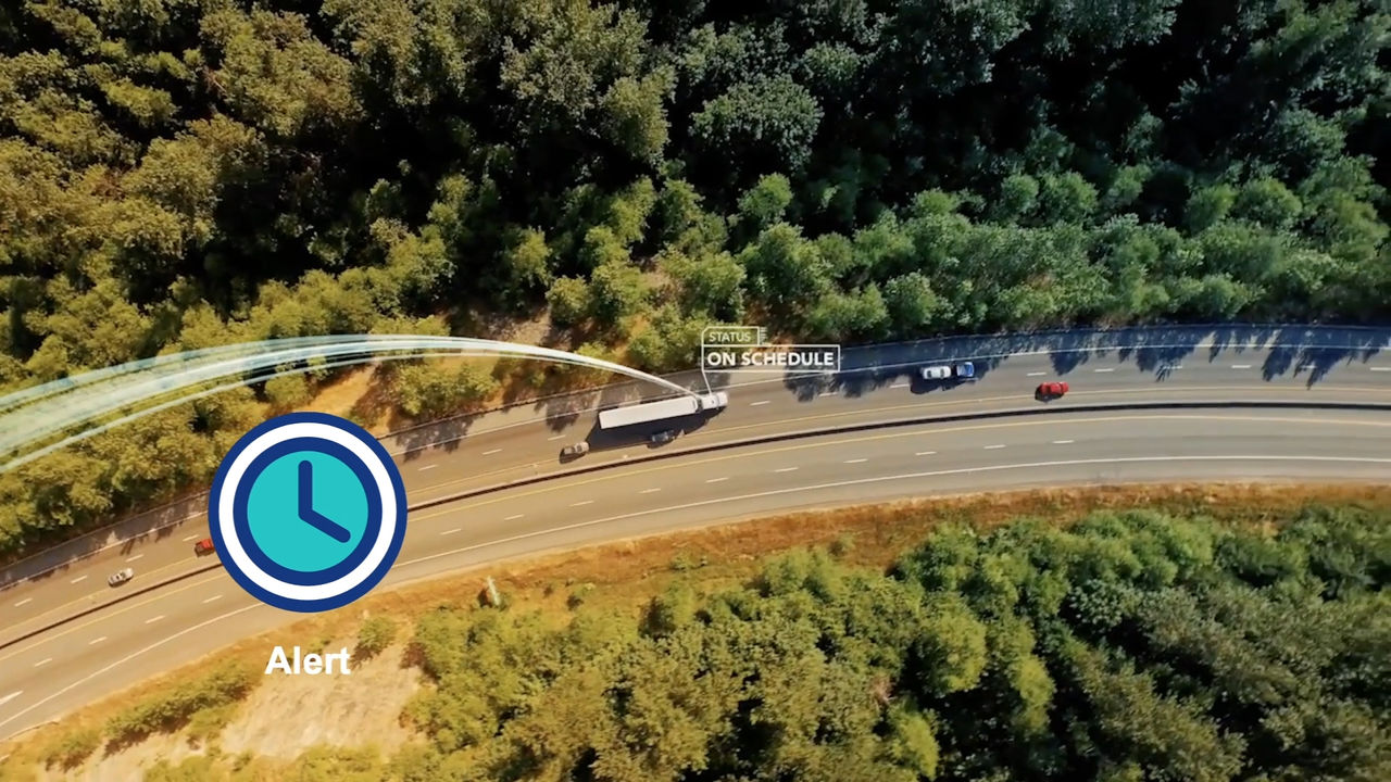 An aerial shot captures a highway surrounded by lush greenery, featuring vehicles in motion.