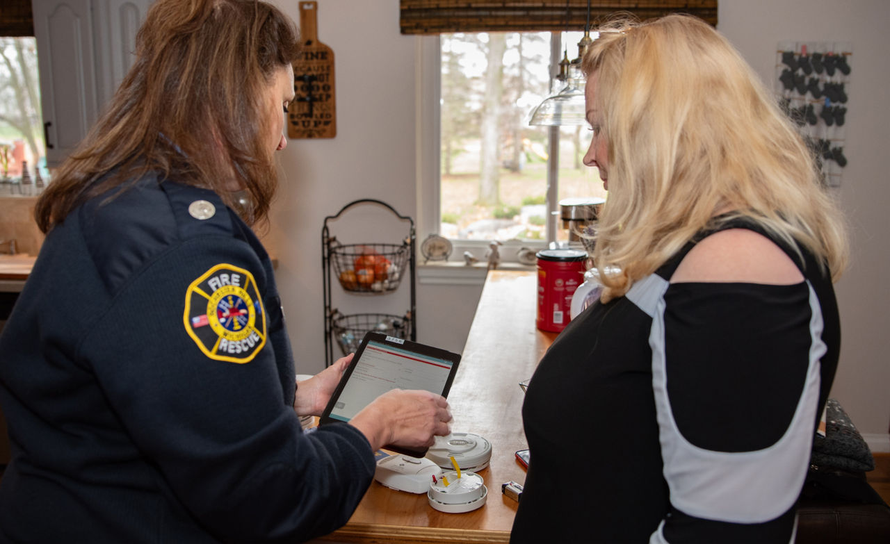  Jenn Whitbeck holds a tablet in her hand to use Survey123 during a smoke and carbon monoxide alarm installation appointment