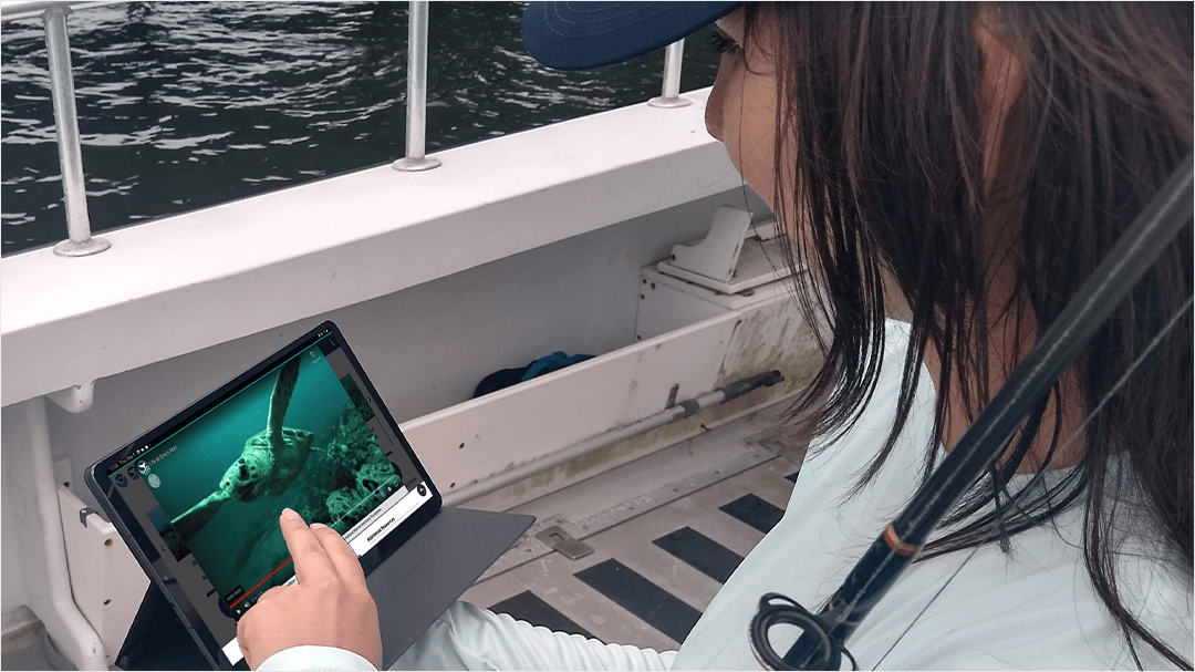 A person holding a fishing pole and a fishing guide displayed on a computer tablet. 