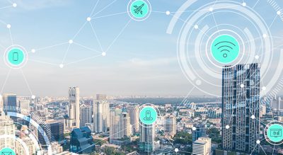 A downtown area of a city with tall buildings overlaid with lines connecting icons representing location and internet connection