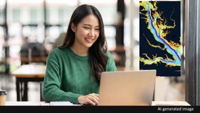 A woman smiling while looking at a laptop which is displaying a colorful map