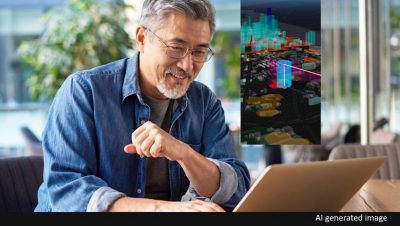 A man wearing glasses looking at a laptop which is displaying a detailed virtual city